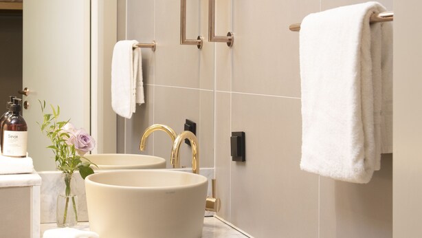 A modern bathroom with a large sink, a mirror, and a towel rack. - Lysebu Hotel (Oslo)