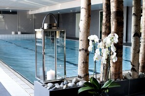 Ein Poolbereich mit einer Glaskuppel, Birken und weißen Orchideen.