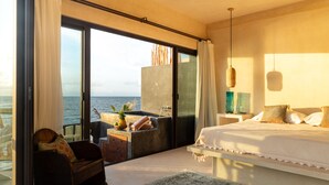 A bedroom with a large bed, a view of the sea, a balcony with a seating area, and a large window. - La Posada del Sol Boutique Hotel Tulum (Tulum)