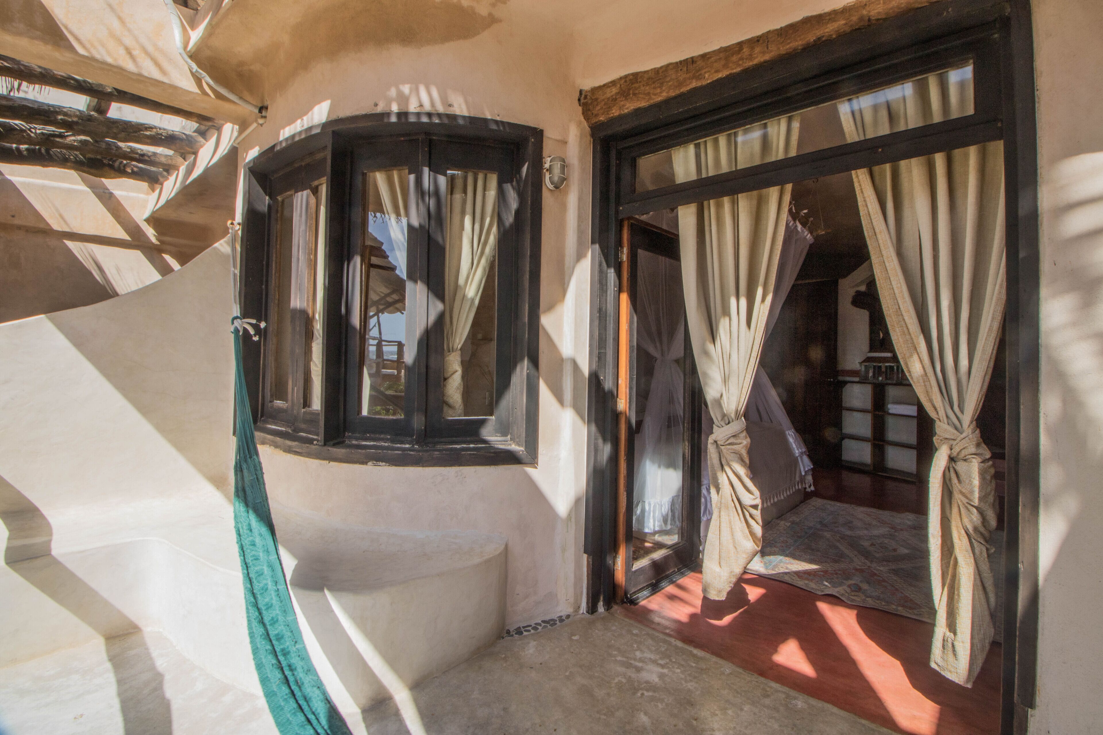 A corner room with a window, a door leading to another room, and a small balcony area.