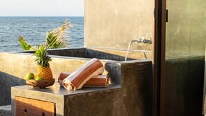 A bathroom with a view of the ocean, a towel, a pineapple, and a basket of fruits. - La Posada del Sol Boutique Hotel Tulum (Tulum)
