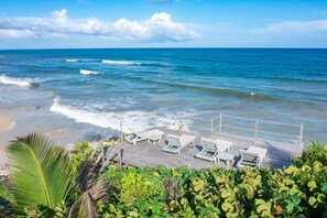 Na praia, espreguiçadeiras, guarda-sóis, toalhas de praia 