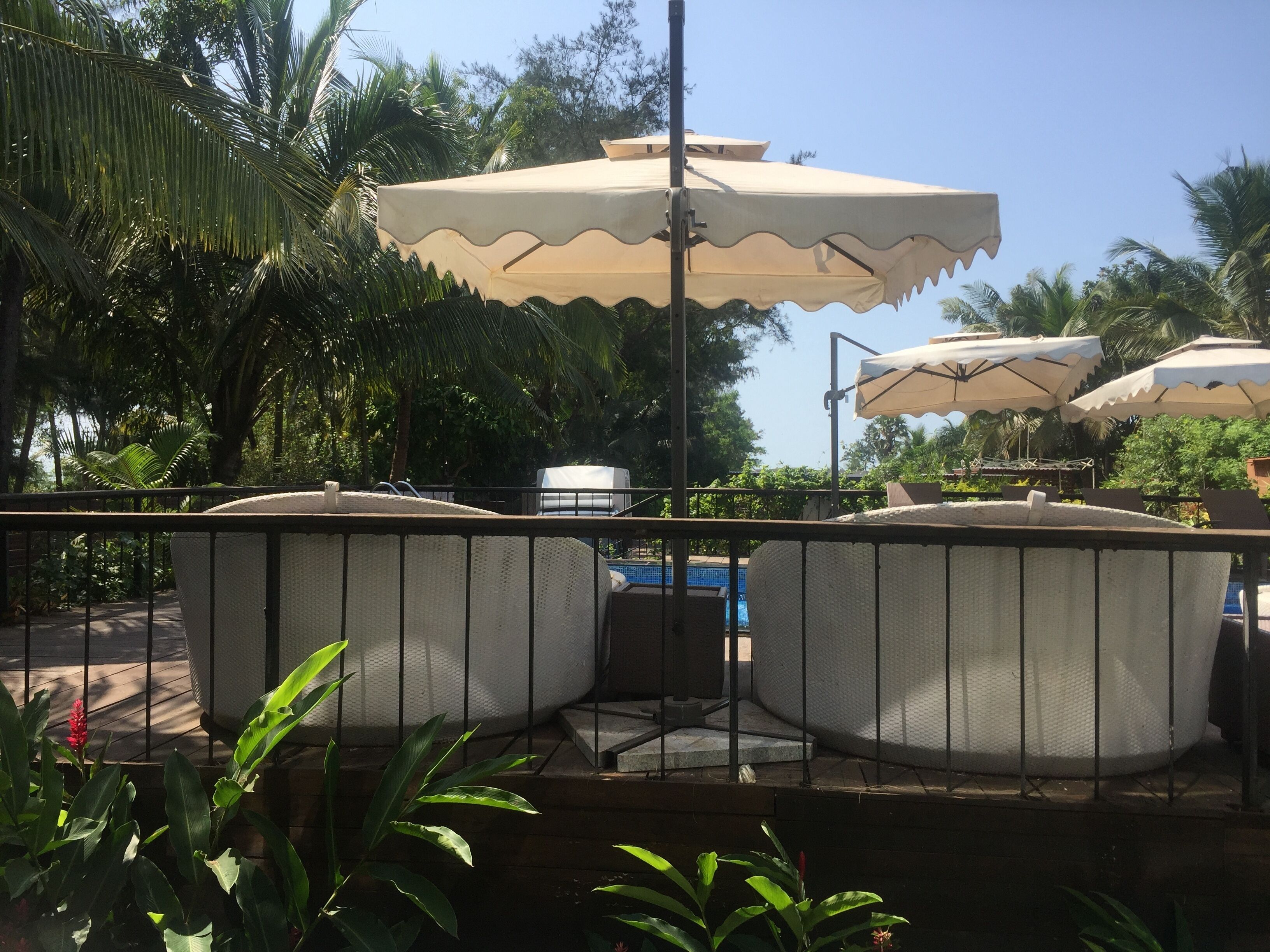Zona junto a la piscina con mobiliario exterior y sombrillas.