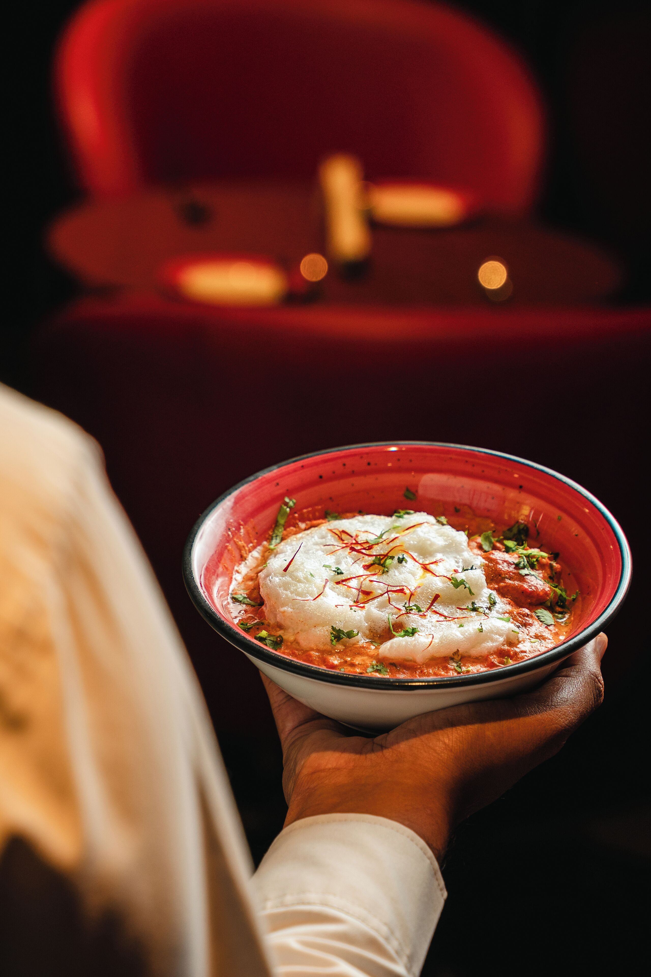 A person holding a bowl of food with a red background.