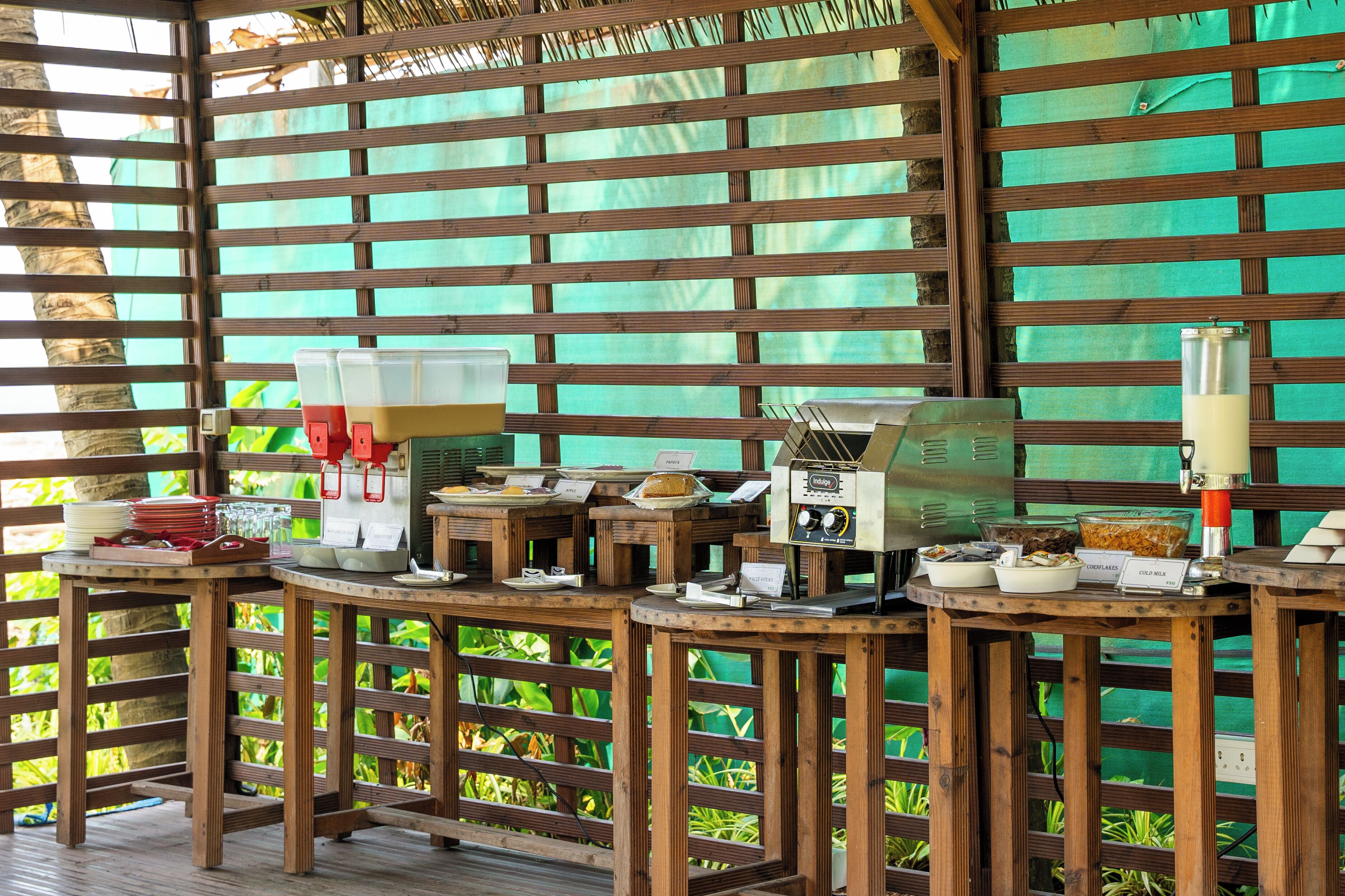 A breakfast buffet setup with various food items and a coffee machine on wooden tables.