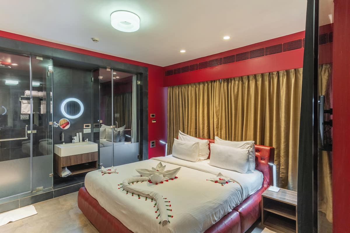 A modern hotel room with a large bed, a vanity with a mirror, and a walk-in closet.