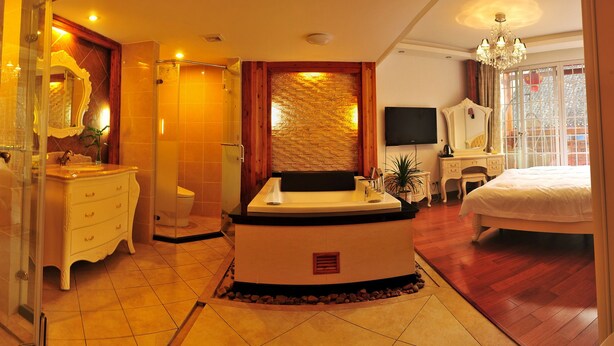 Une chambre d’hôtel avec salle de bain, un lit, une télévision et un lustre.