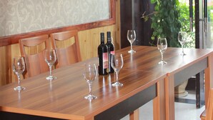 Un coin repas avec une table en bois, six chaises et quatre verres à vin.