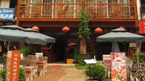 Un complexe hôtelier traditionnel construit en bambou, avec une structure à plusieurs étages, des balcons et un espace de détente extérieur.