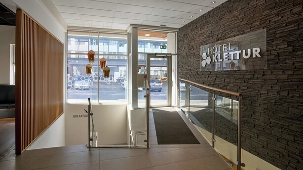 A modern hotel lobby with a stone wall, a glass entrance, and a sign reading "HOTEL KLETTUR". - Hotel Klettur (Reykjavik)
