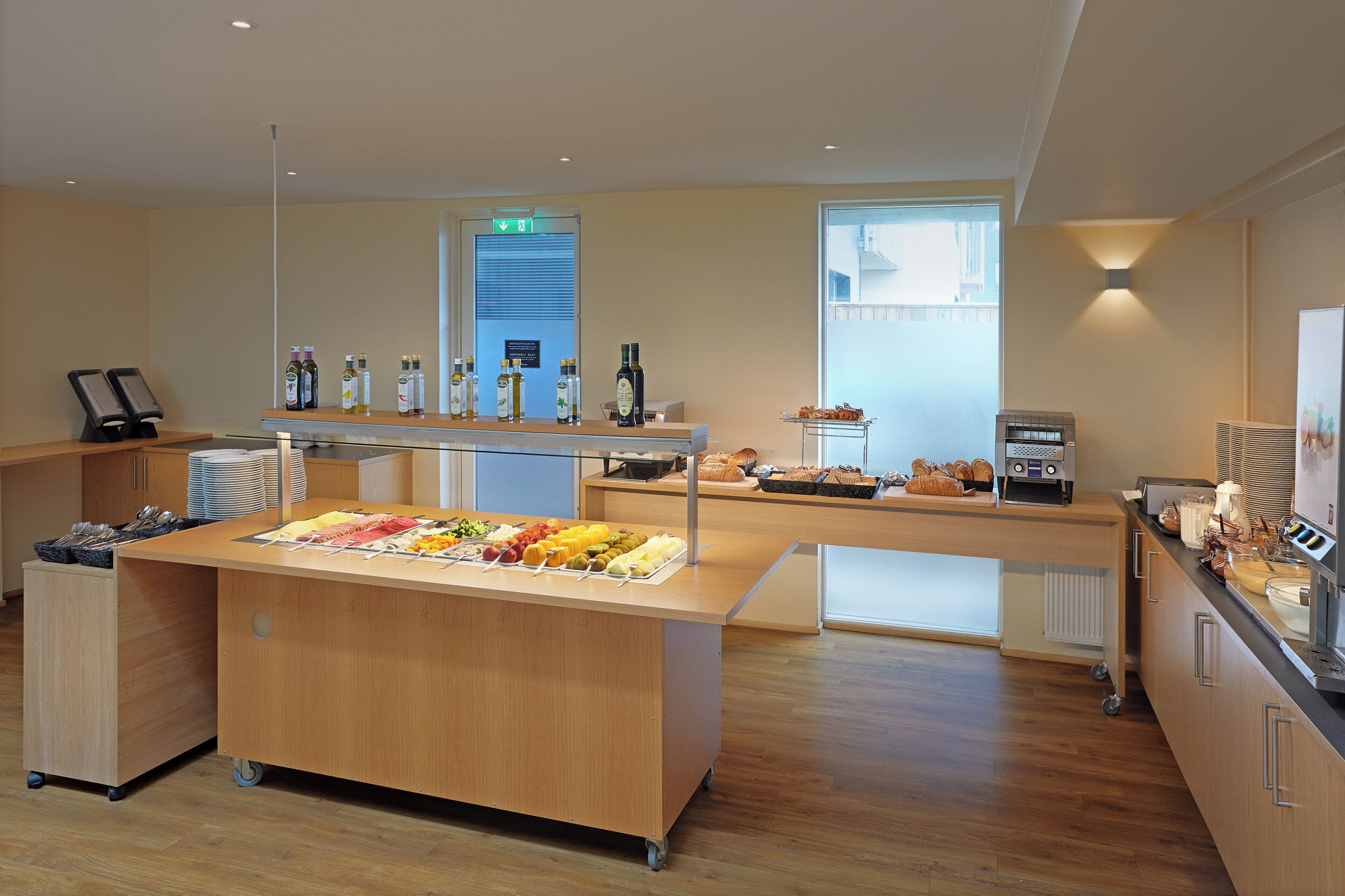 A modern kitchen area with a buffet setup, including various food items and condiments.
