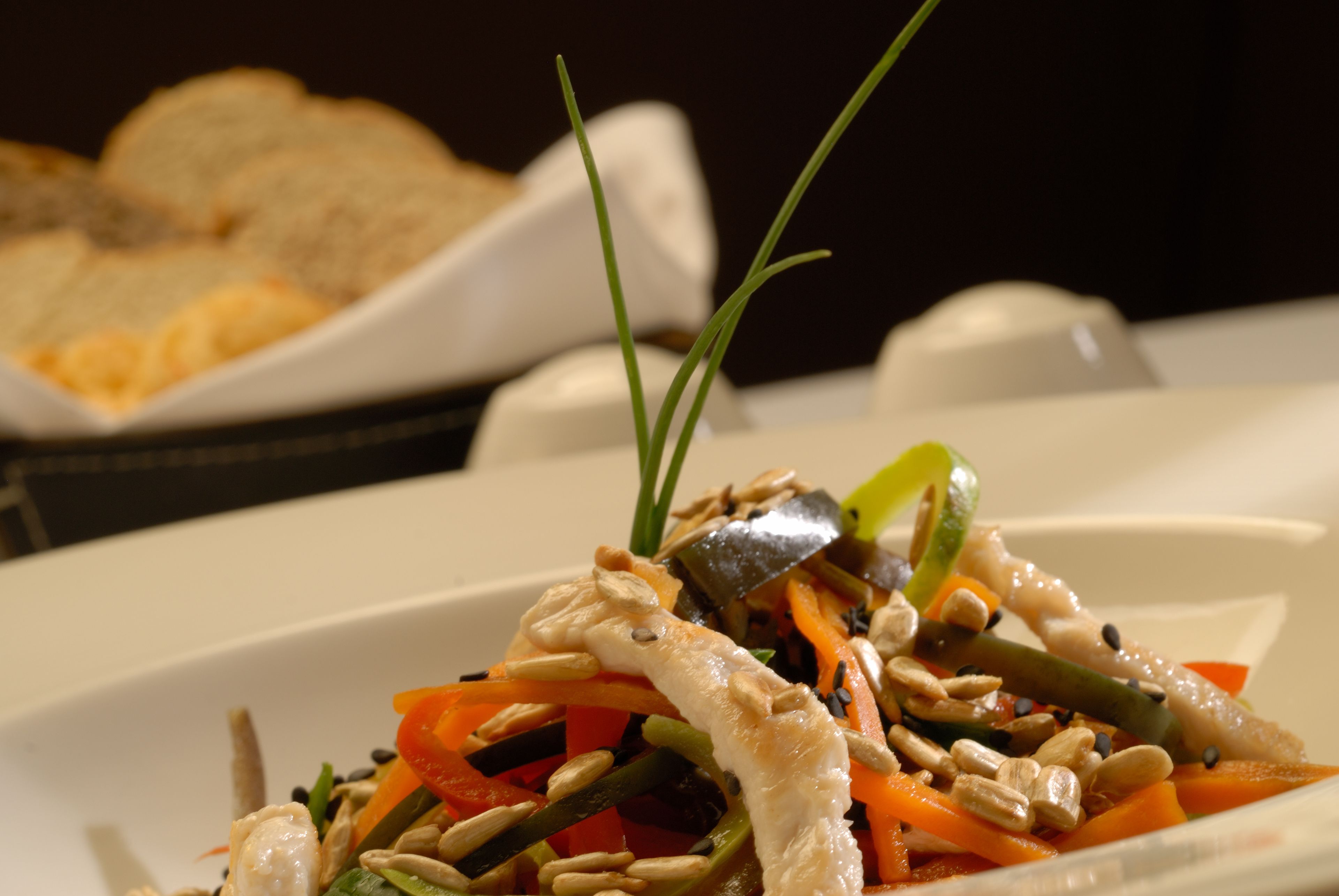 A plate of stir-fried vegetables with a piece of chicken, garnished with green onions and sesame seeds.
