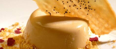 A dessert with a caramelized base, a creamy center, and a crispy top, garnished with red flakes and a drizzle of sauce.