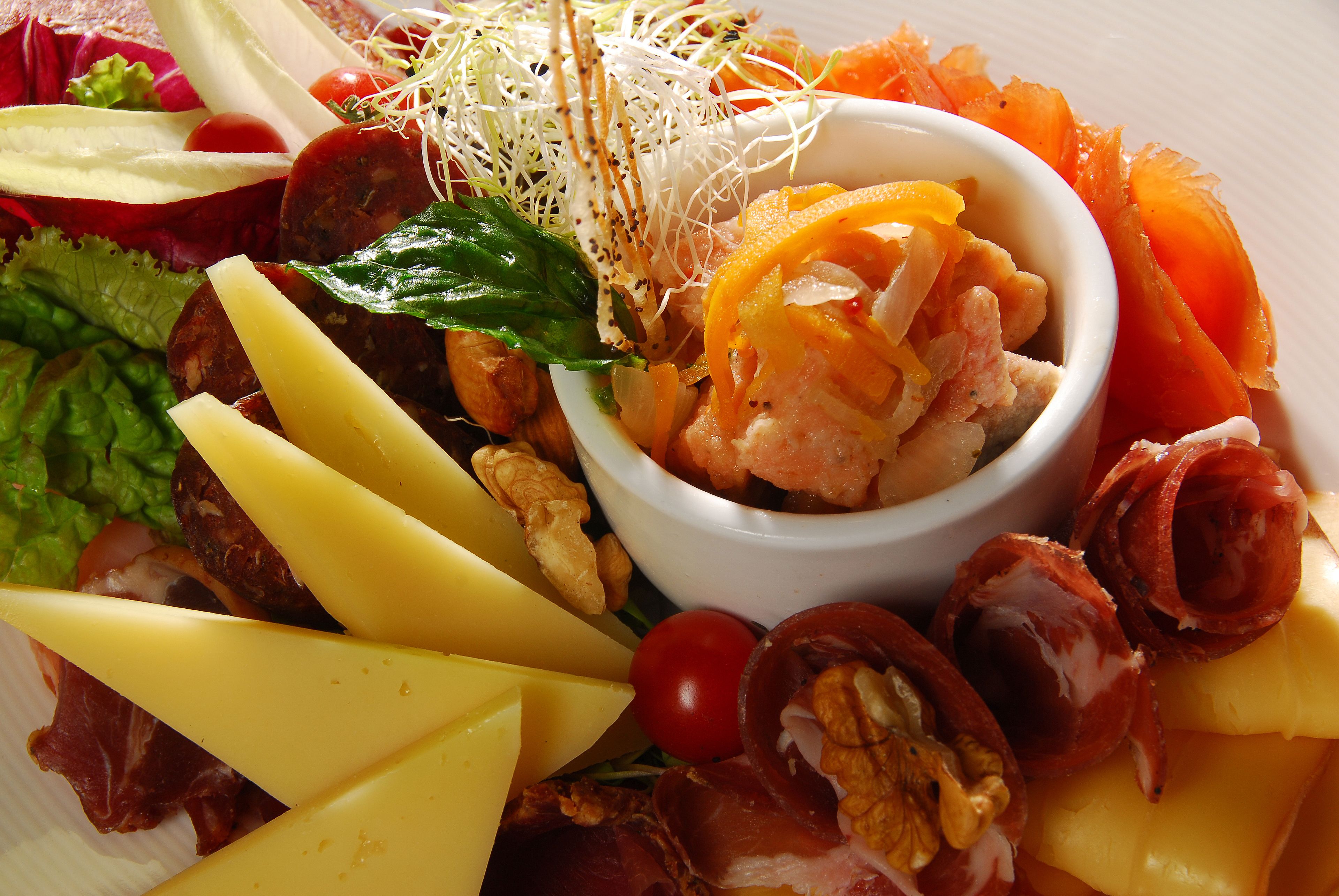A platter of assorted cheeses, meats, and vegetables.