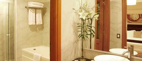 Un baño moderno con ducha de vidrio, una bañera independiente, un lavabo con espejo y reflejo del ambiente.