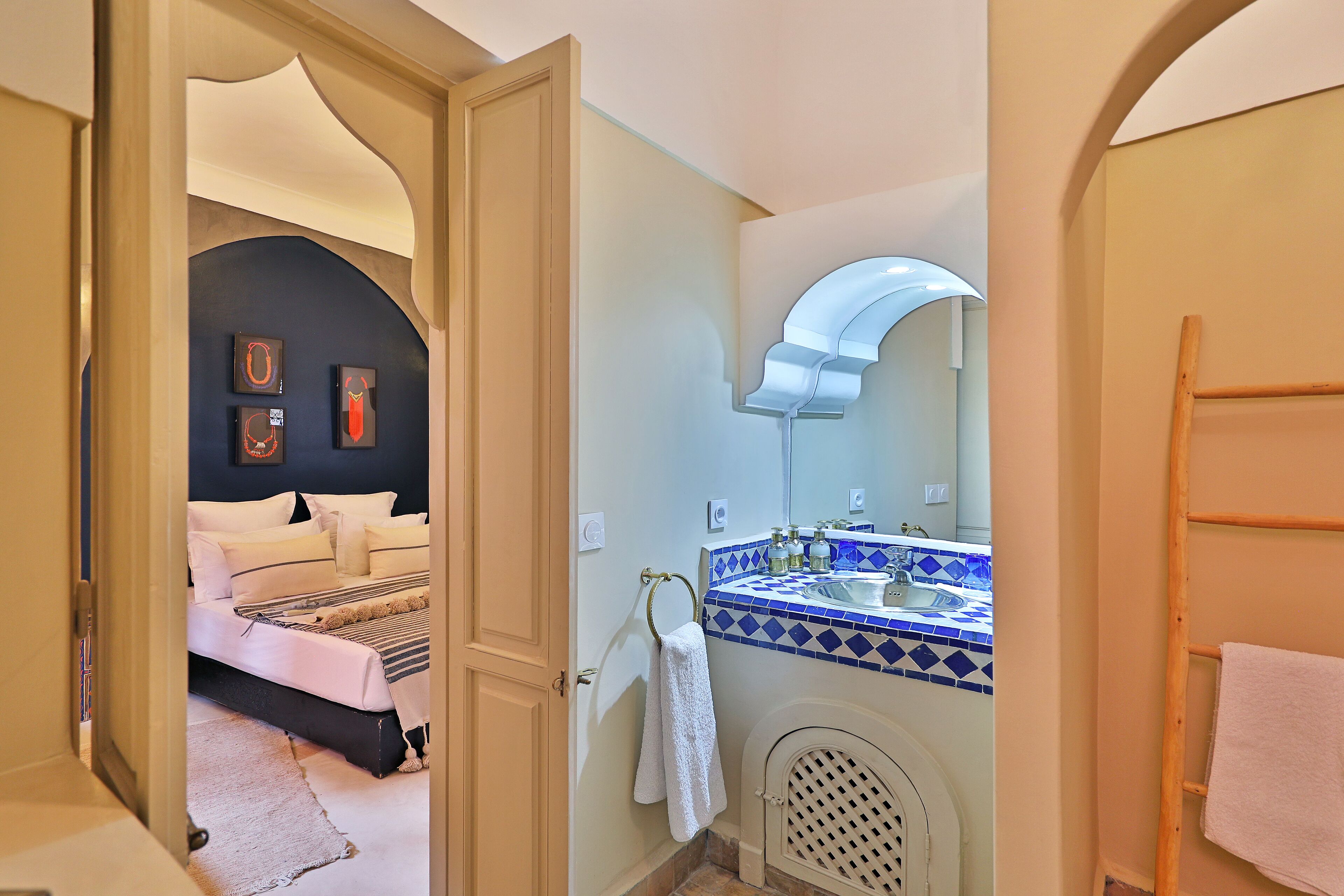 Une chambre avec un lit, une salle de bain avec un lavabo et un miroir, et un couloir.