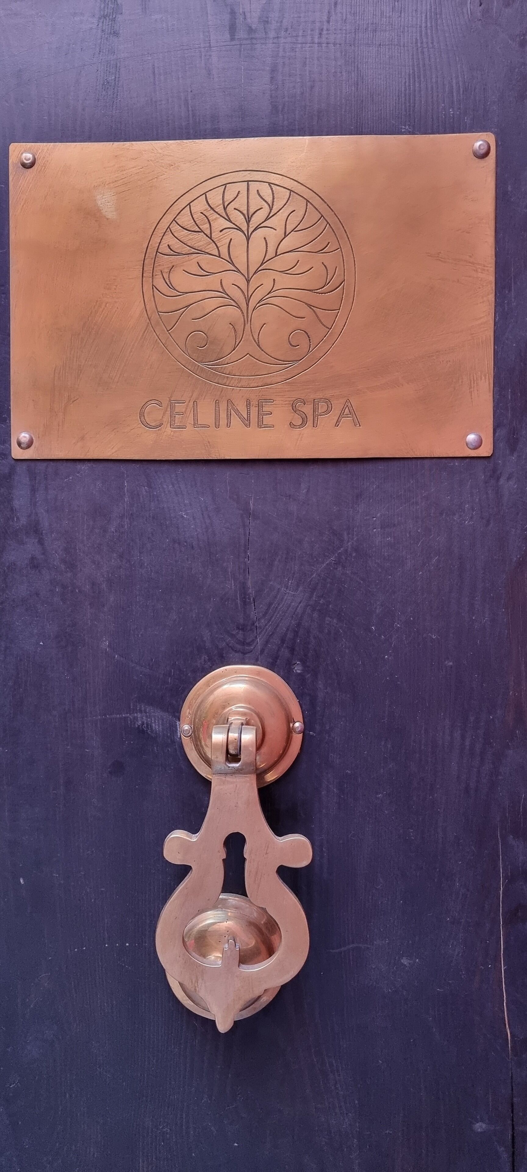 A wooden door with a brass plaque reading "CELINE SPA" and a brass door knocker.