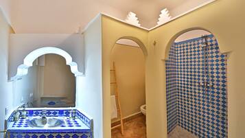 Un baño con un salpicadero de azulejos blancos y azules a cuadros, un lavamanos blanco y una ducha con pared de azulejos blancos y azules a cuadros.
