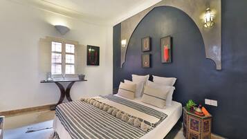 Un dormitorio con cama, mesita de noche, escritorio y ventana.