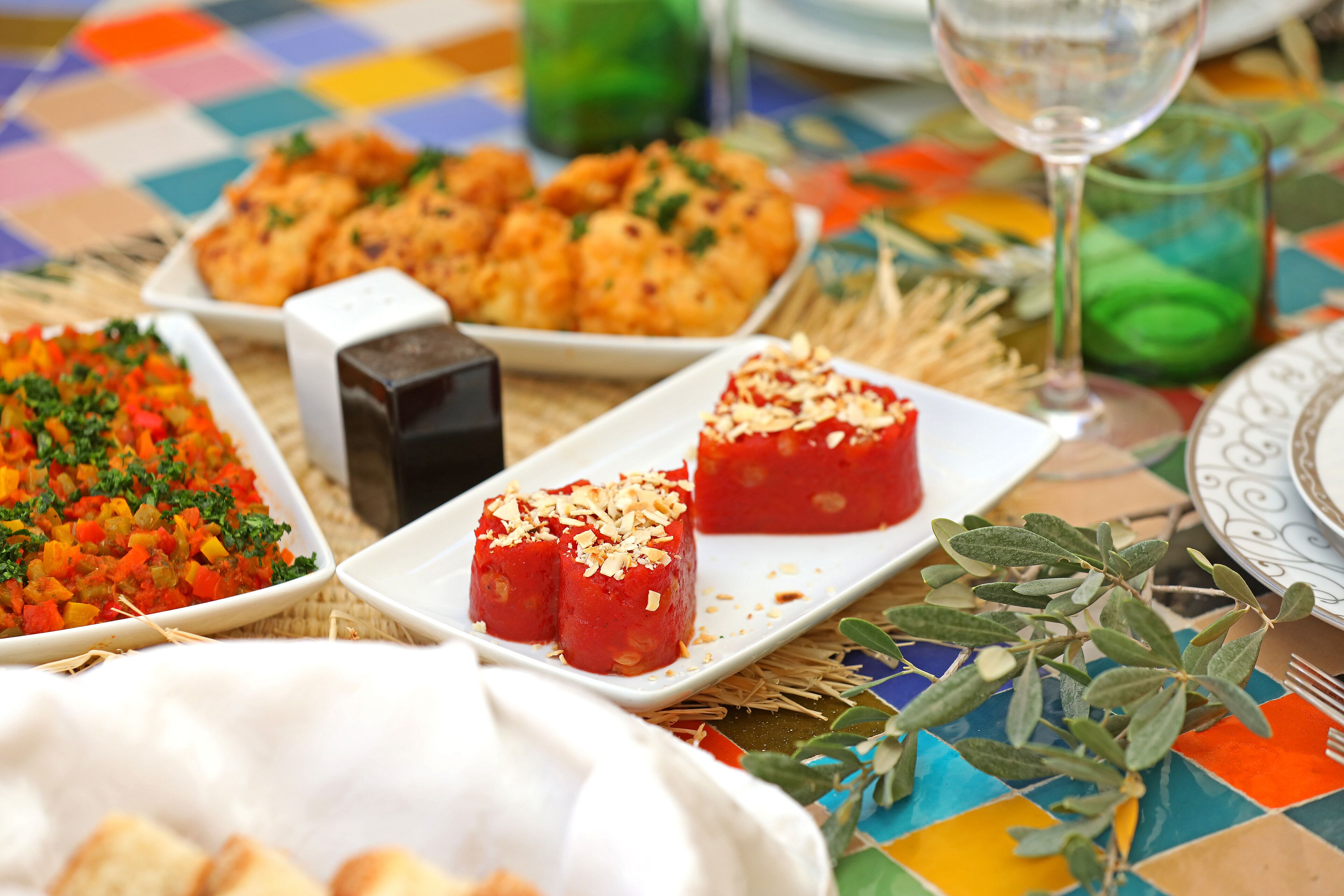A table with various dishes, a glass of wine, and a decorative plant.