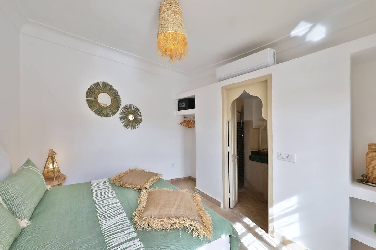 A bedroom with a bed, a hanging light fixture, and decorative wall mirrors.