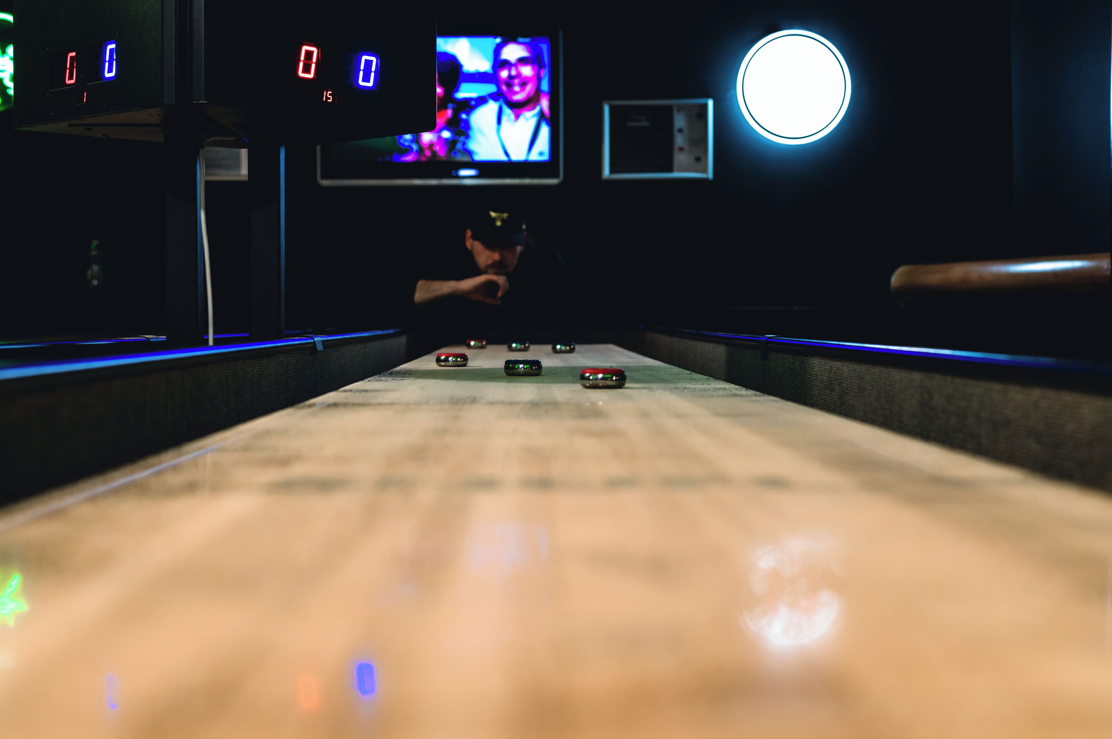 Une salle de bowling avec des pistes, une boule de bowling et un écran de télévision sur lequel est affiché l’image d’une personne.