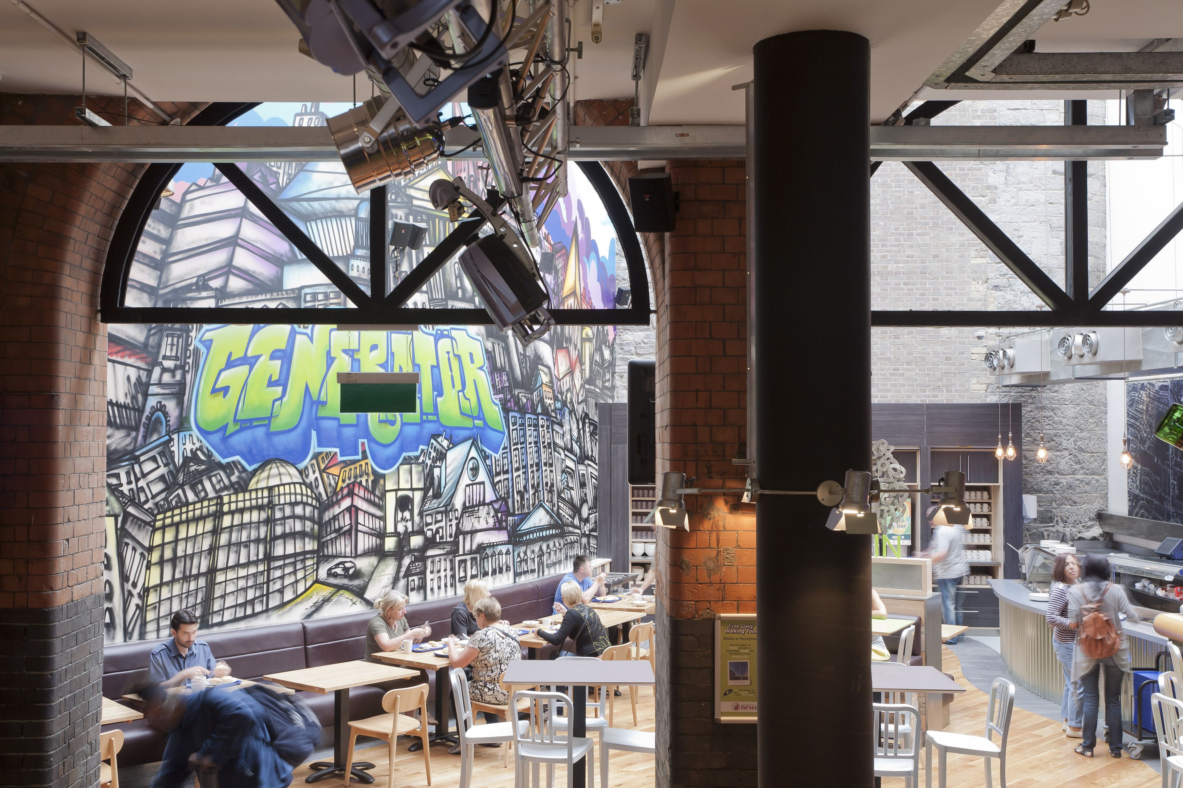Ein Café mit Wandgemälde einer Stadtansicht, Tischen und Stühlen für die Bewirtung von Gästen.
