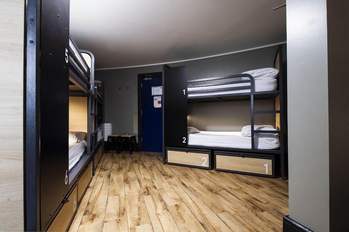 Un dormitorio con literas, suelo de madera y un escritorio pequeño.