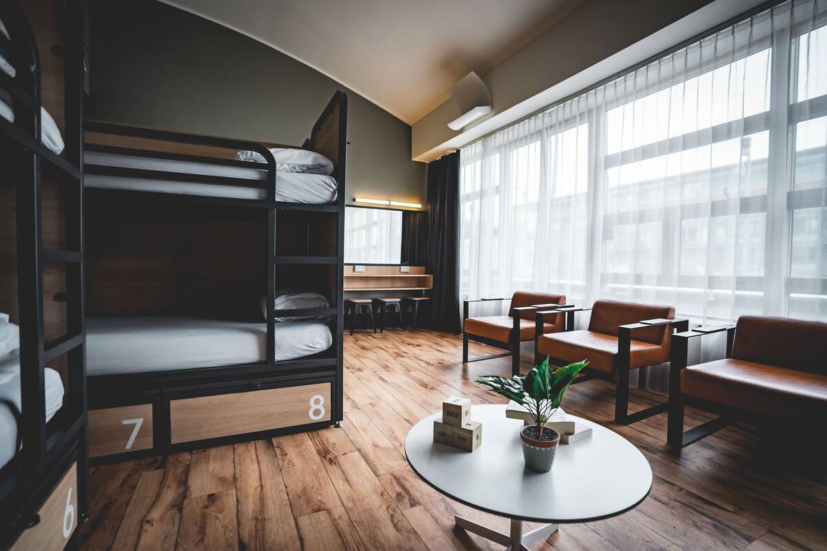 A room with bunk beds, a round table with a plant, and leather chairs.