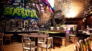 Een restaurantinterieur met graffiti kunst, houten meubels en een bakstenen muur.