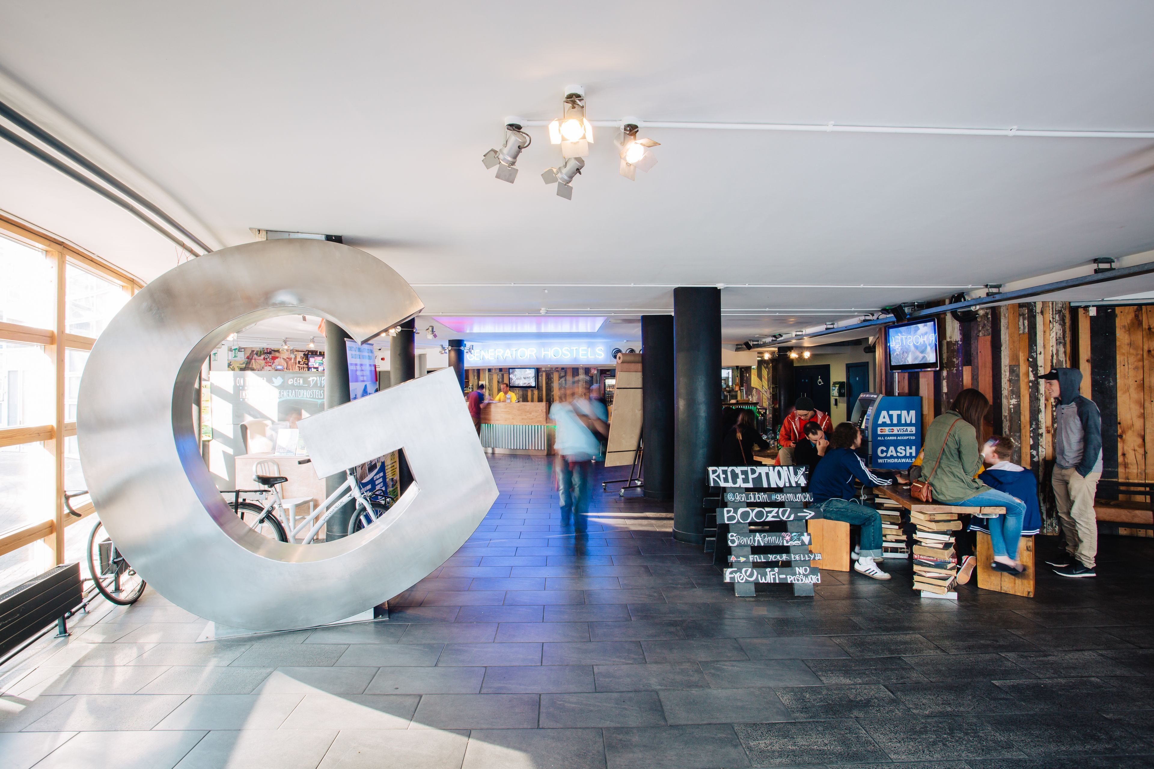 A modern interior with a large metallic sculpture, a reception area, and a seating area with books.