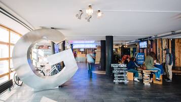 A modern interior with a large metallic sculpture, a reception area, and a seating area with books.