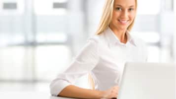 Una persona sentada en un escritorio con una computadora portátil en un ambiente de oficina moderno y luminoso.