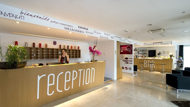 A reception area with a wooden counter, a bar, and a staircase leading to the upper floor.
