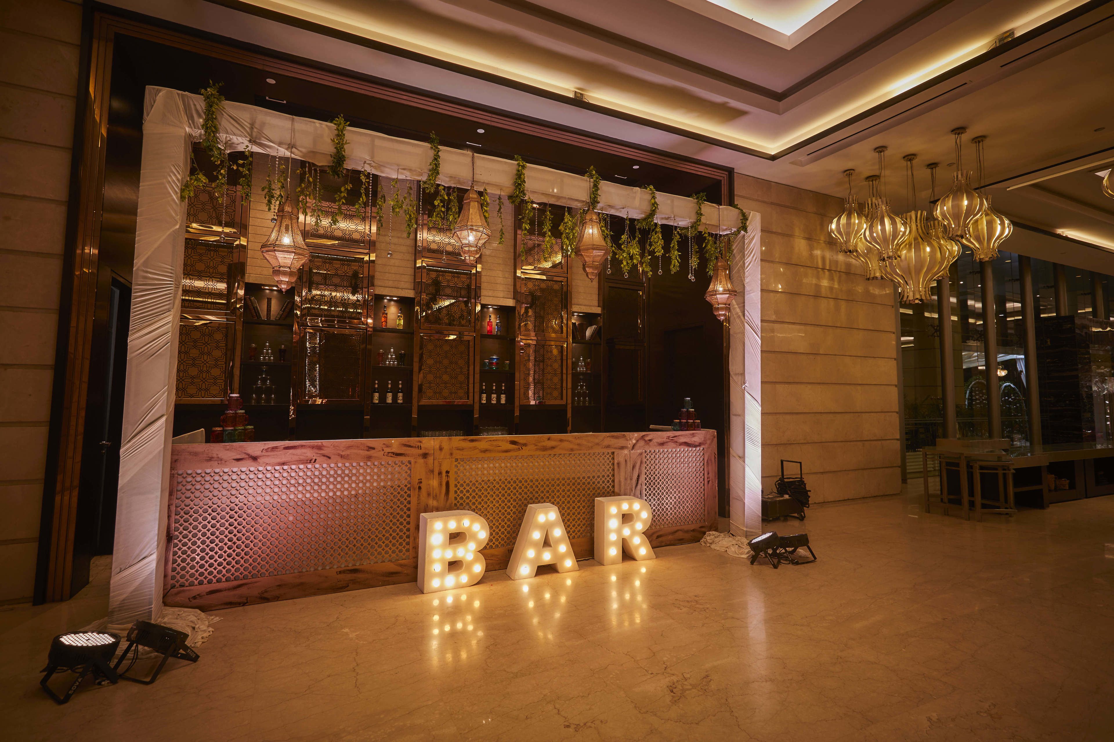 A bar area with illuminated 'BAR' letters, hanging plants, and a well-lit interior.