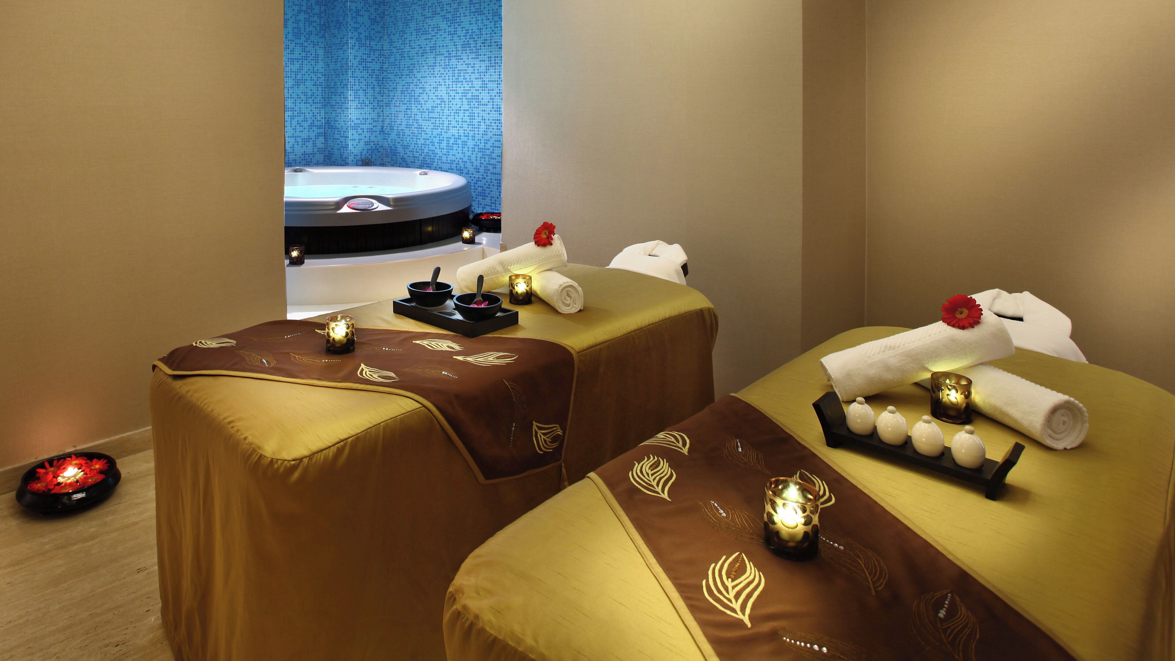 Een spa-ruimte met twee massagetafels, elk voorzien van handdoeken en kaarsen.
