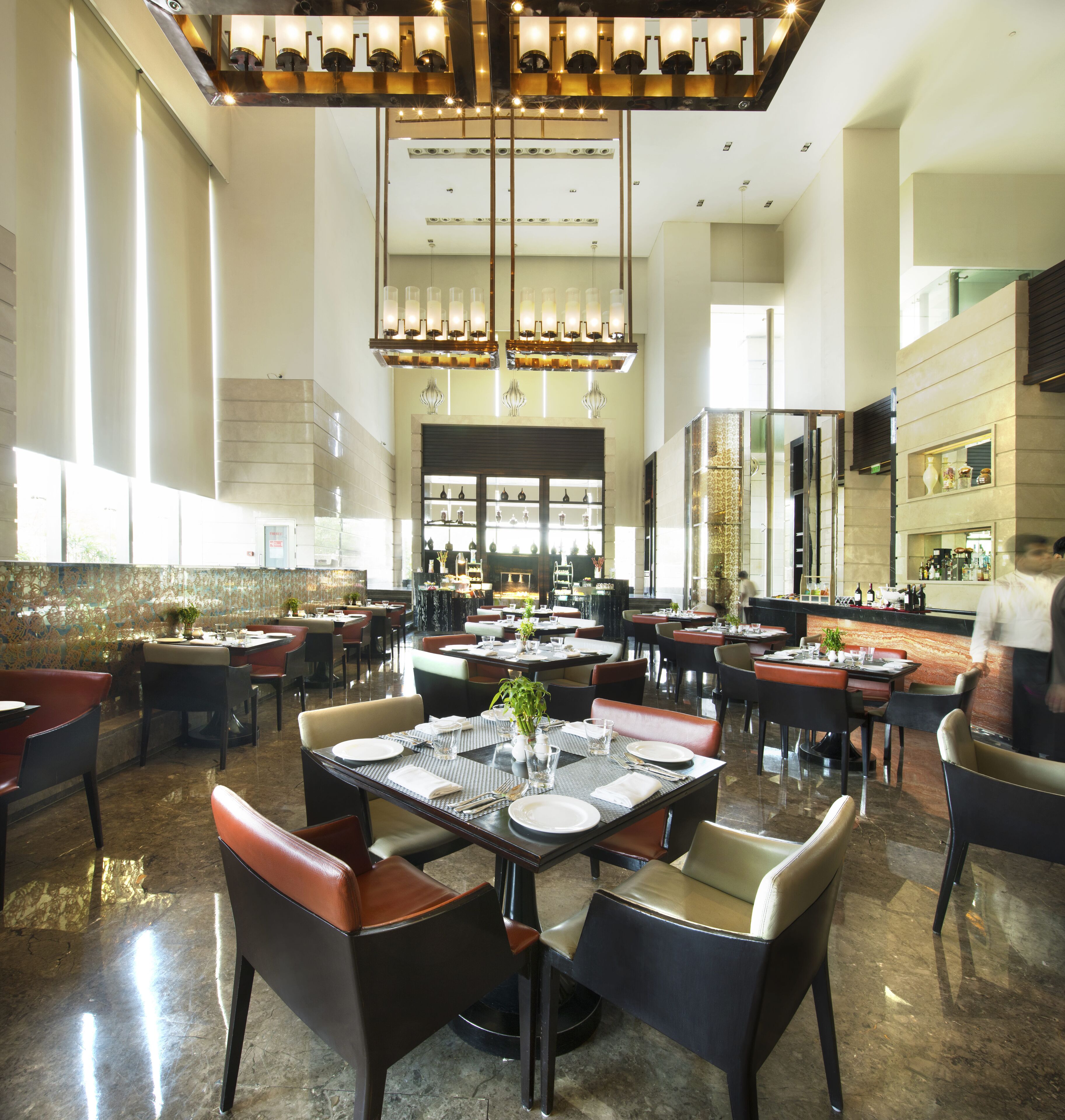 A spacious restaurant with high ceilings, modern chandeliers, and a variety of seating arrangements.