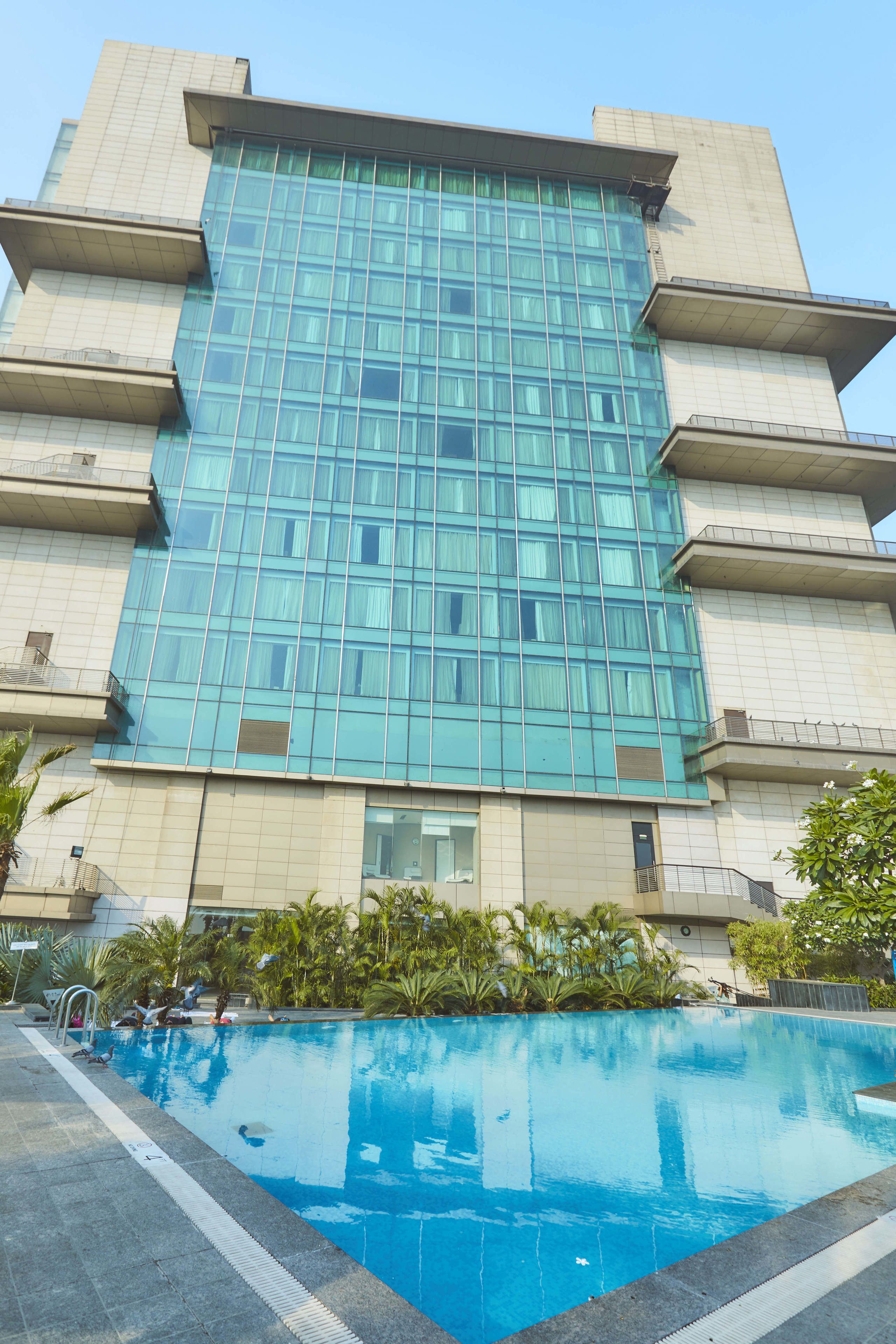 Um edifício moderno com fachada de vidro extensa e piscina em frente.