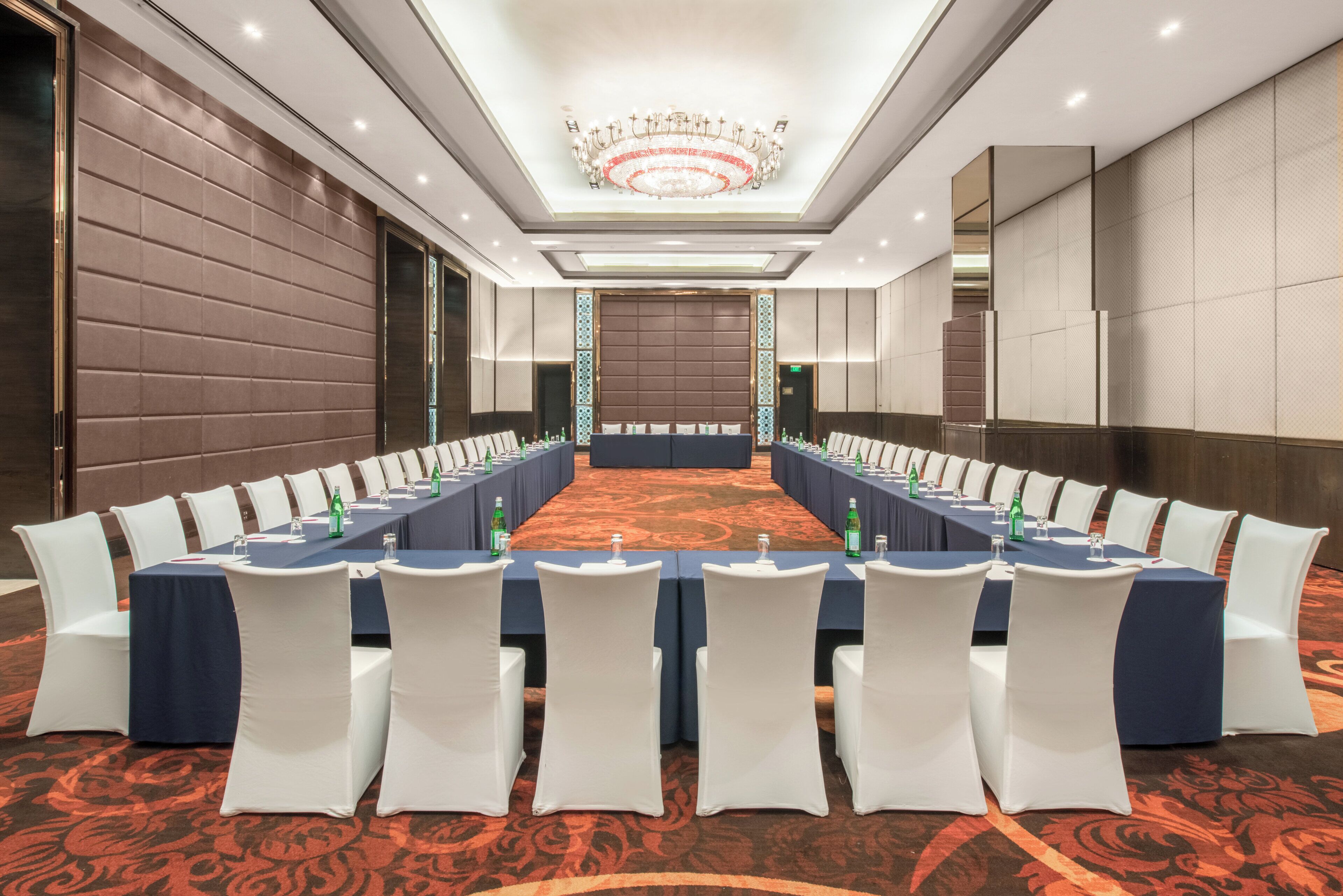 A conference room with a long table, white chairs, and a chandelier.