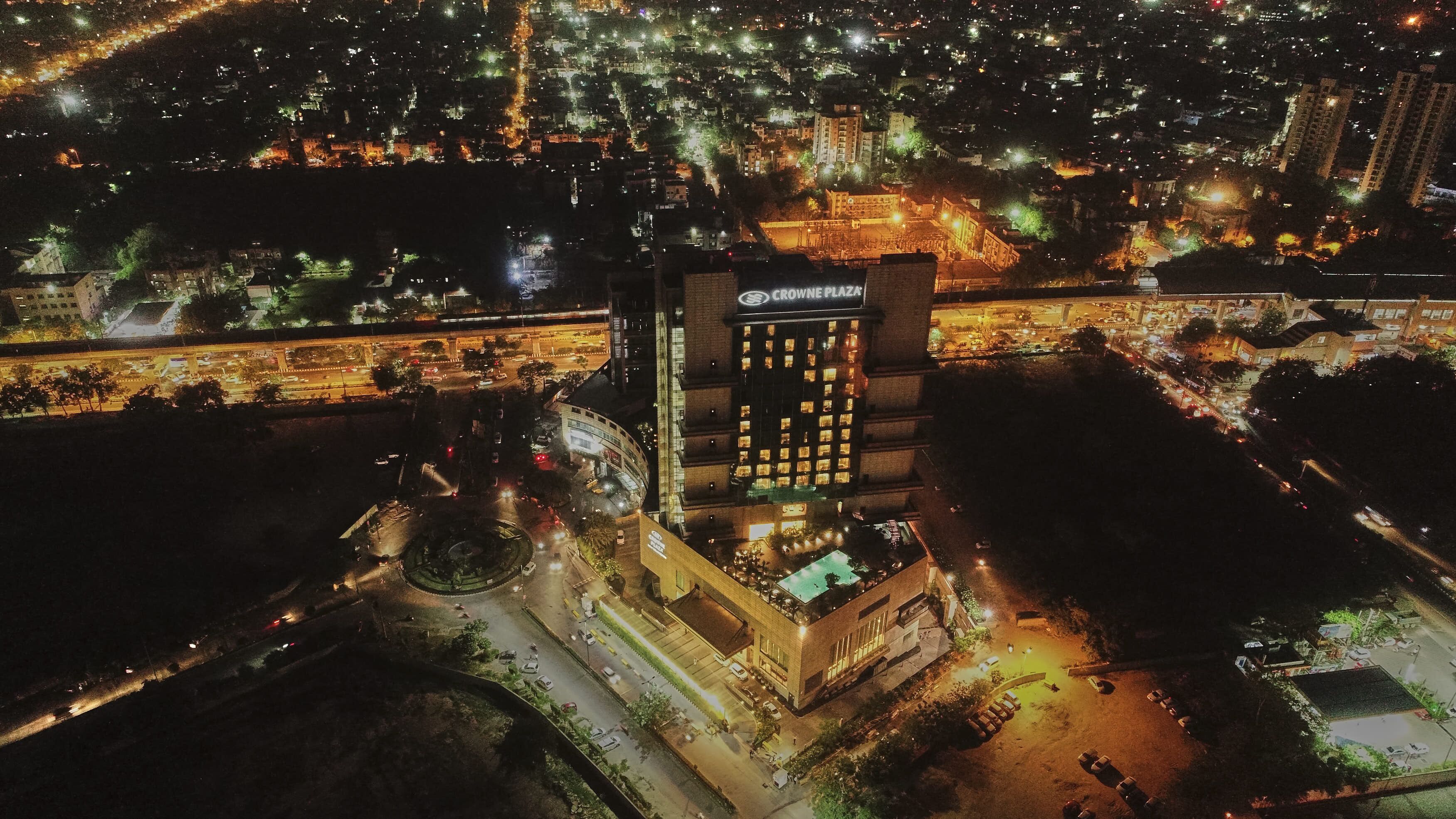 An aerial view of a cityscape at night with a prominent building labeled "Crowne Plaza."