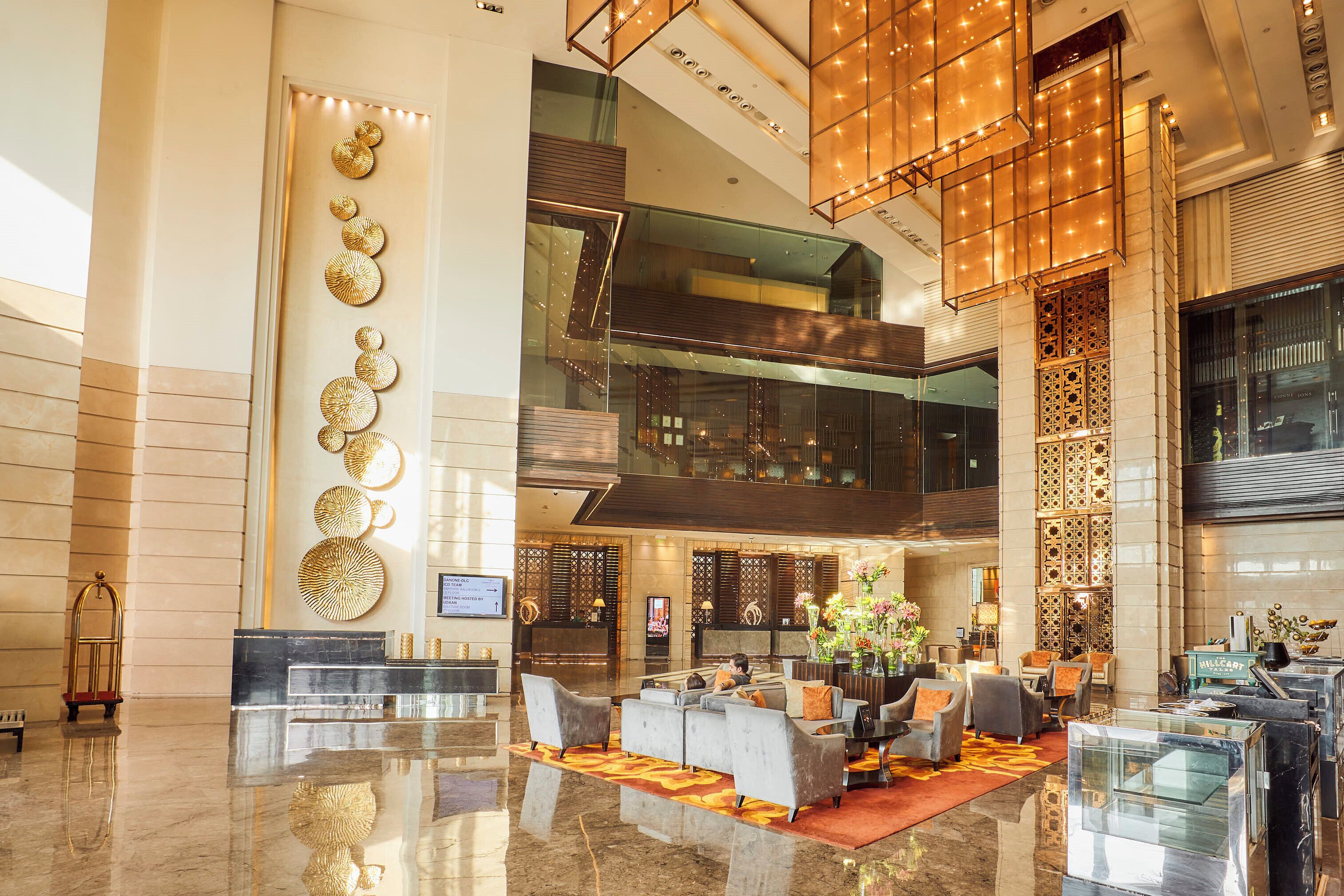 A spacious lobby with a reception desk, seating area, and a large decorative wall.