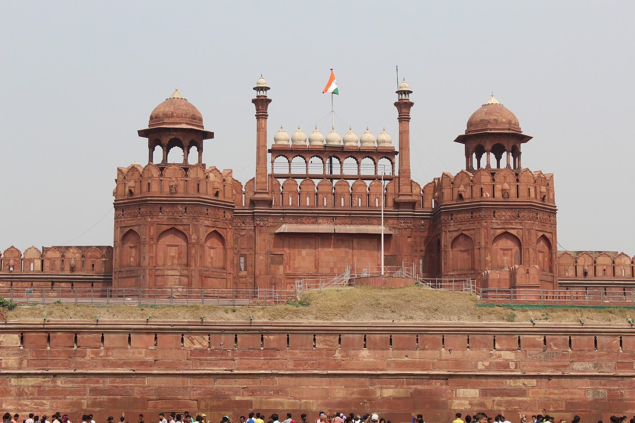 A large, historic building with multiple domes and arches, featuring a prominent flag.
