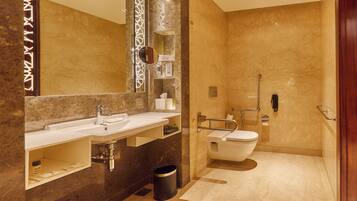 Un baño moderno con lavamanos de mármol, un espejo grande, un inodoro y una zona de ducha.