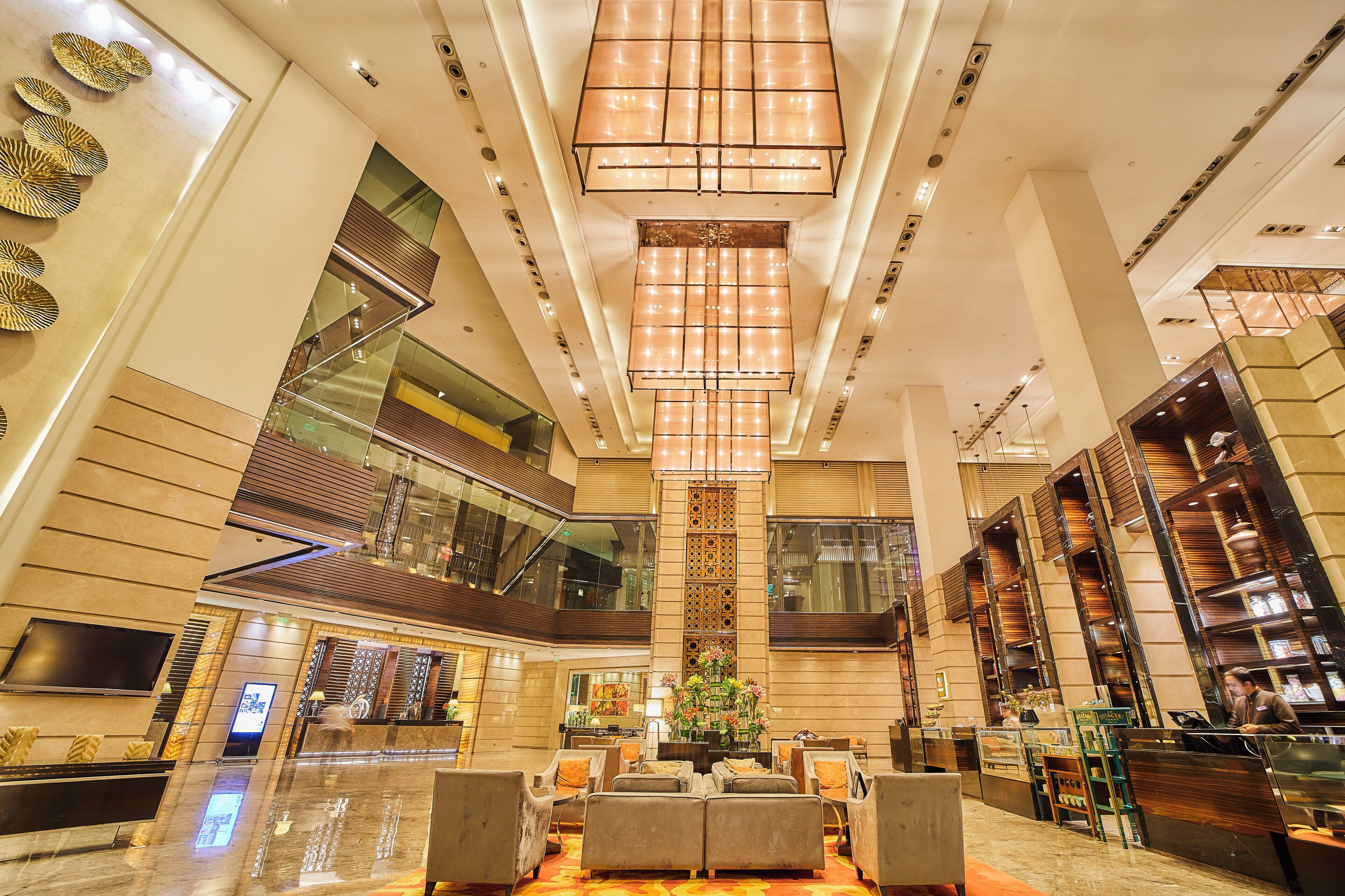 A spacious lobby with a high ceiling, a central chandelier, and a reception desk.