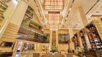A spacious lobby with a high ceiling, a central chandelier, and a reception desk.