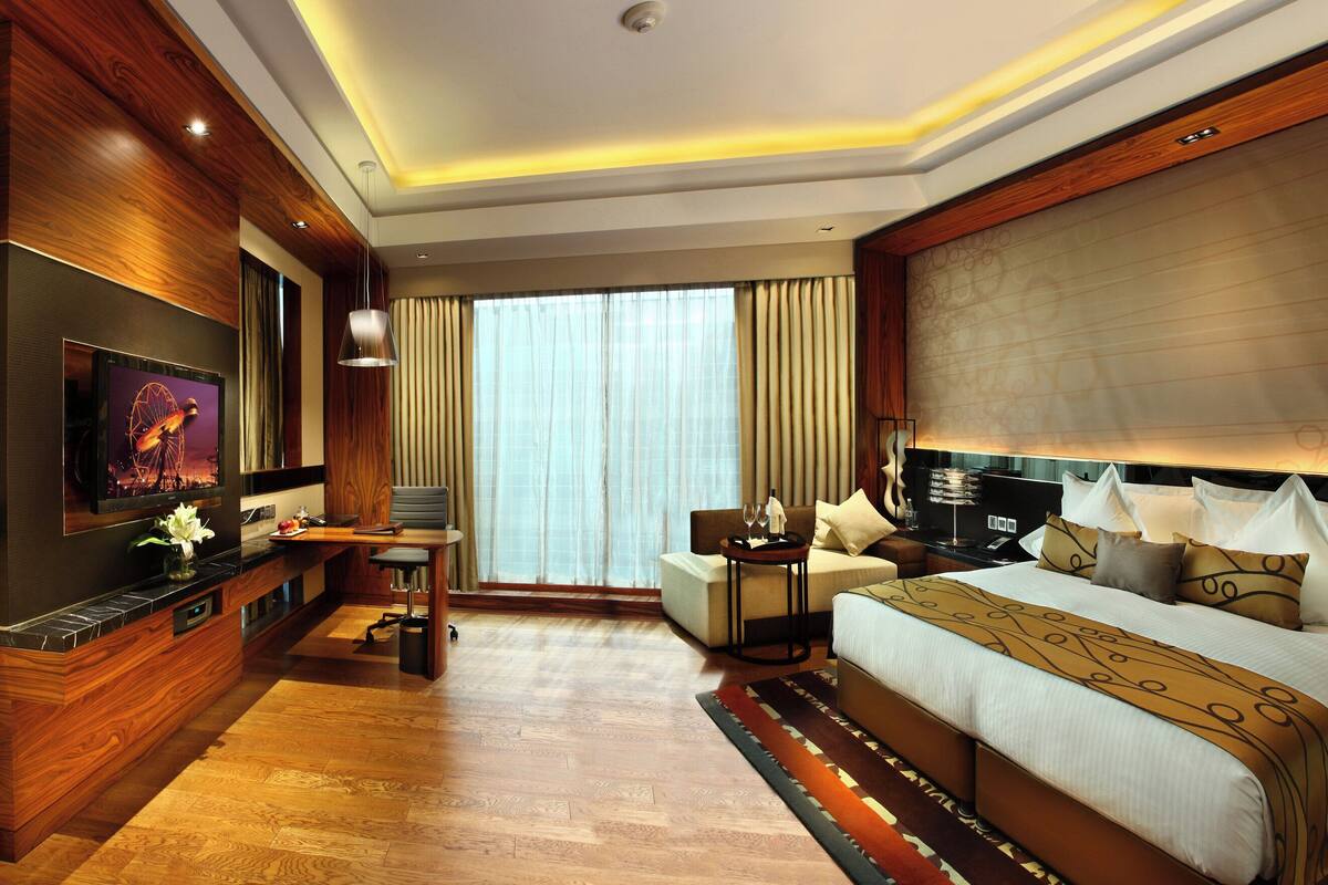 Una habitación de hotel moderna con una cama grande, un escritorio, un televisor y vistas a la ciudad.