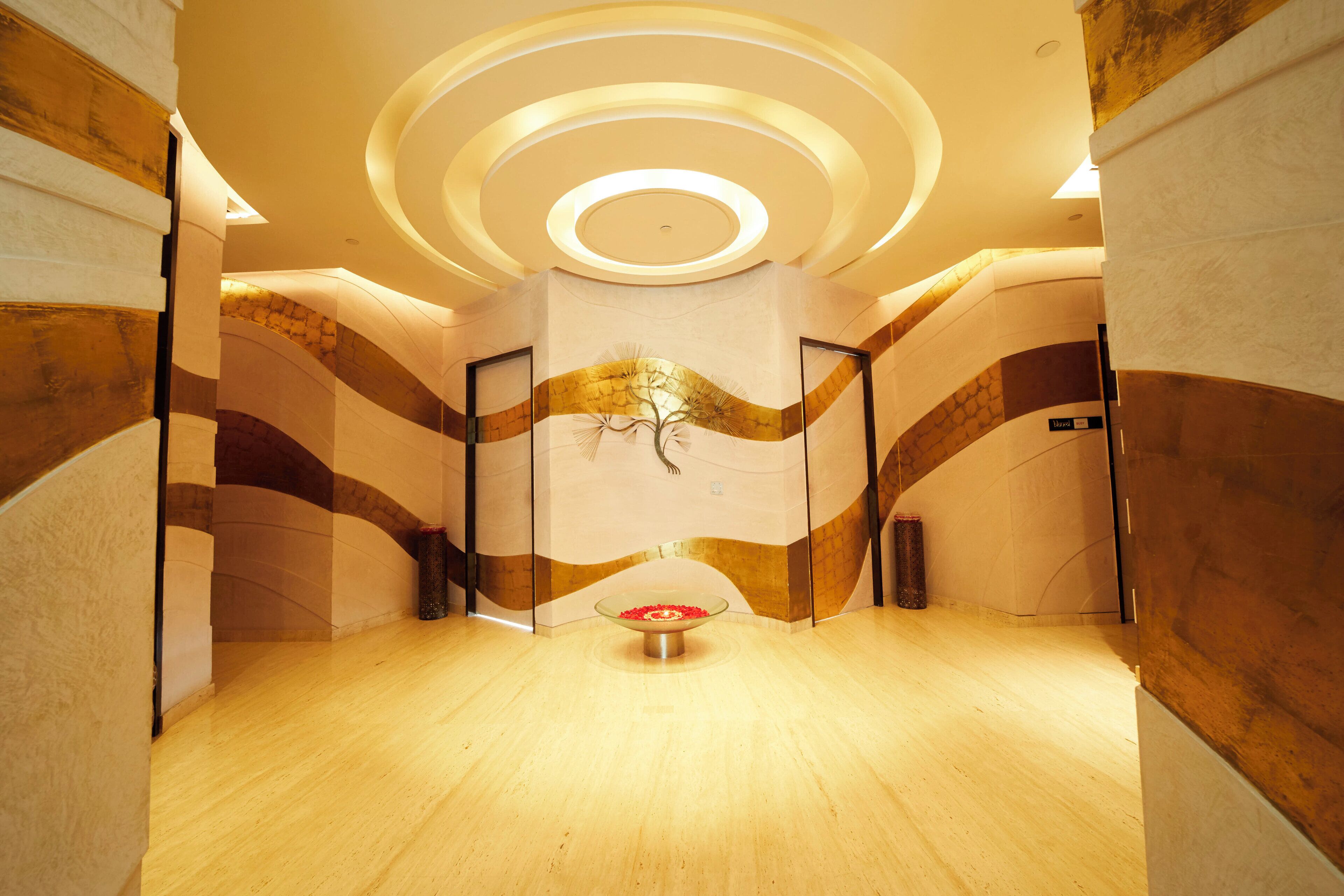 A modern interior with a circular ceiling design, a central art piece, and a wooden floor.