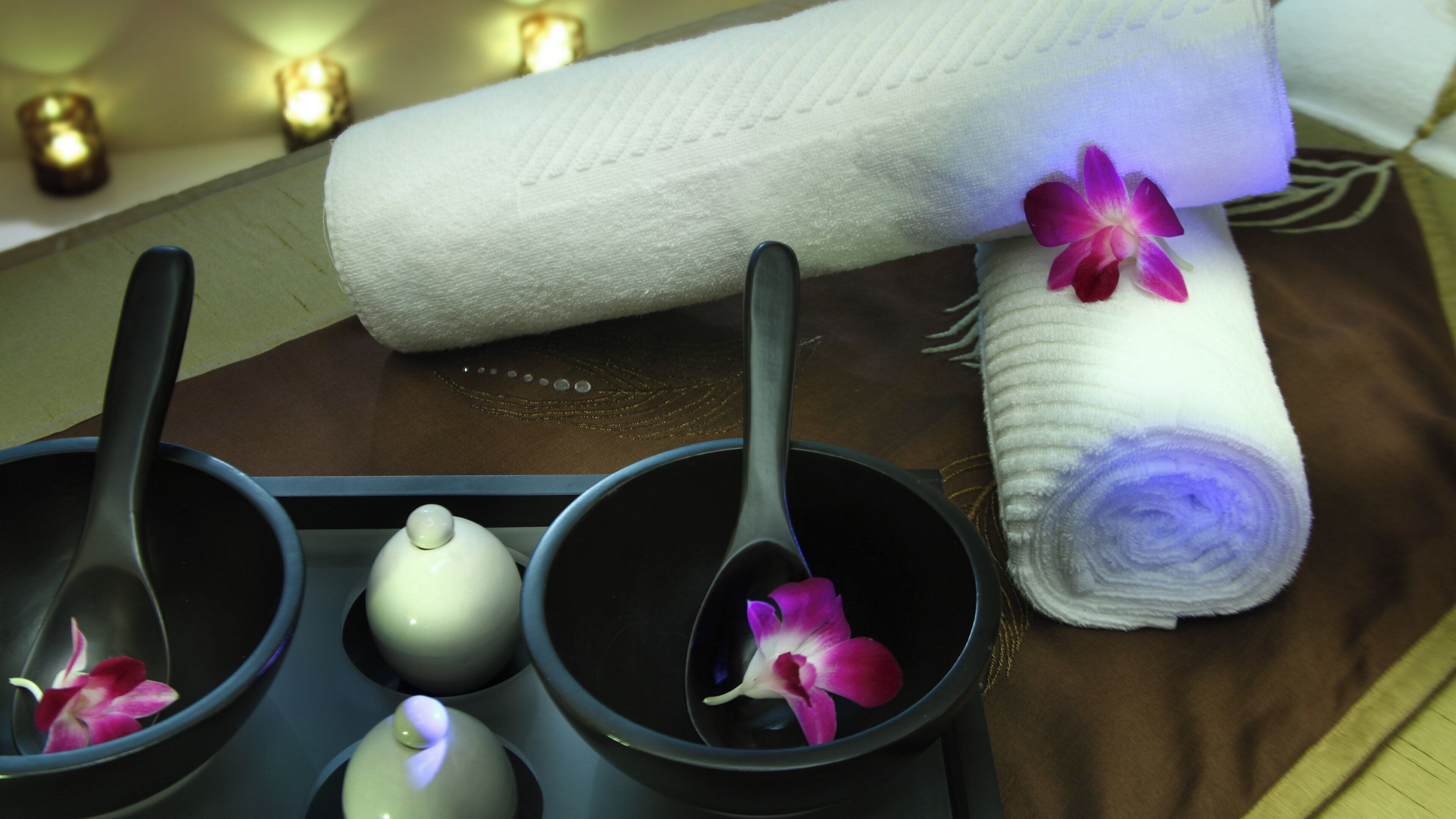 Een wellness omgeving met een handdoek, twee kommen, een theepot en een bloem.