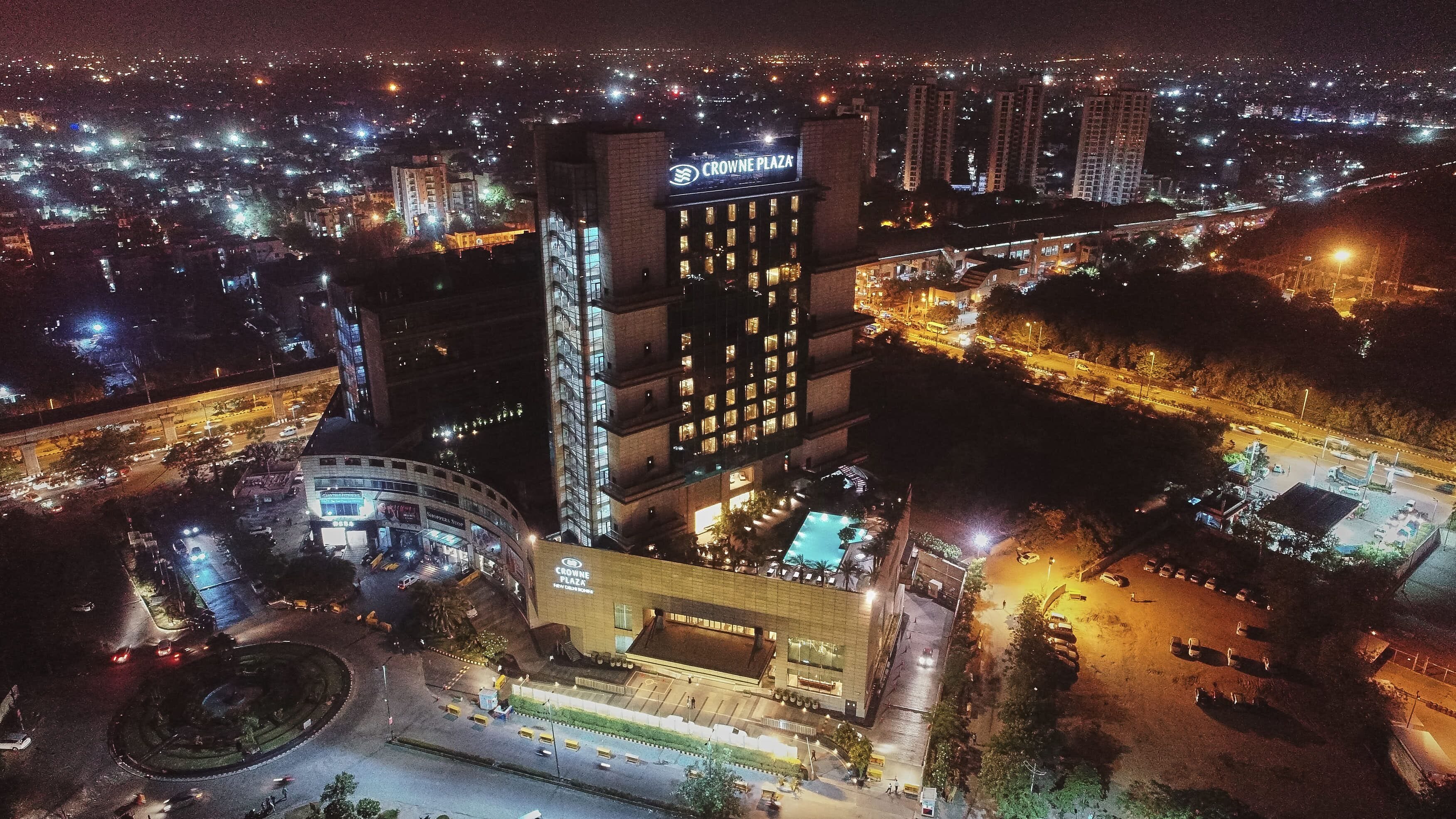 A high-rise hotel with a prominent sign, a swimming pool, and a parking area.