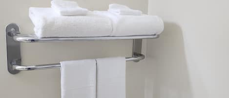 Un baño con un perchero que sostiene toallas dobladas y un inodoro a la vista.